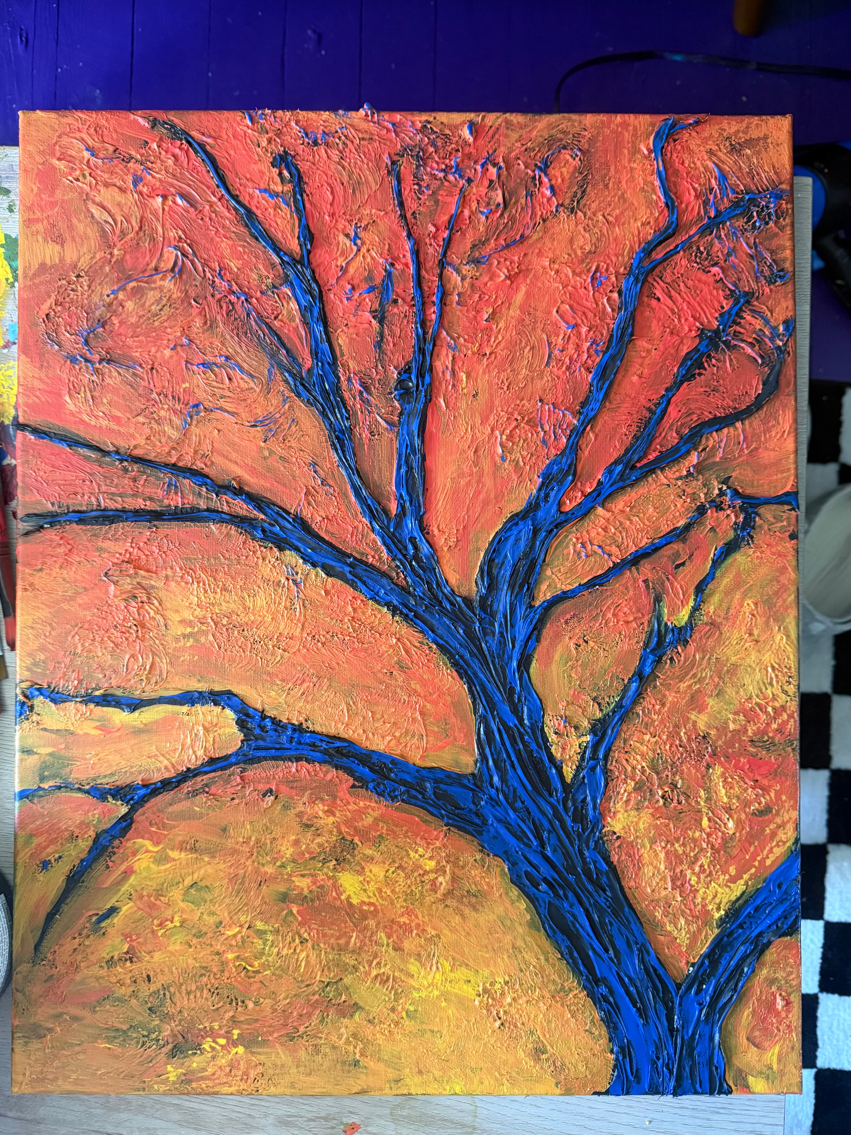 Big Blue Fall Tree — original 14×18 caulk art tree painting for sale by Jay the Painter, Akron Ohio. Massive cobalt blue tree blazing against firestorm of autumn oranges reds and golds, thick raised 3D caulk texture branches. One of a kind original painting.