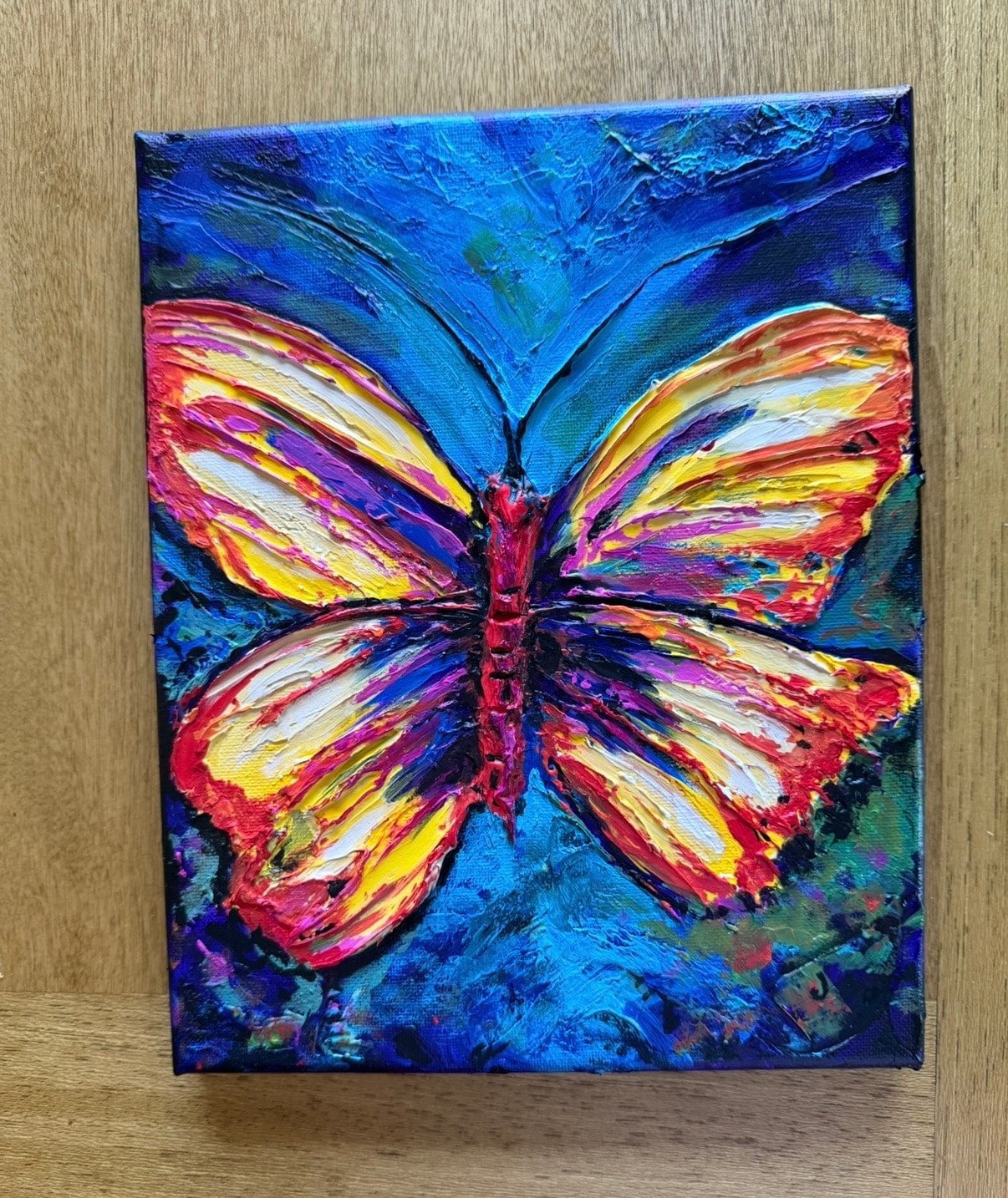 Butterfly — original 8x10 inch caulk texture painting by Jay the Painter, Akron Ohio. Bold butterfly wings in yellow red orange and purple with massive raised caulk ridges on deep cobalt blue background. SOLD.
