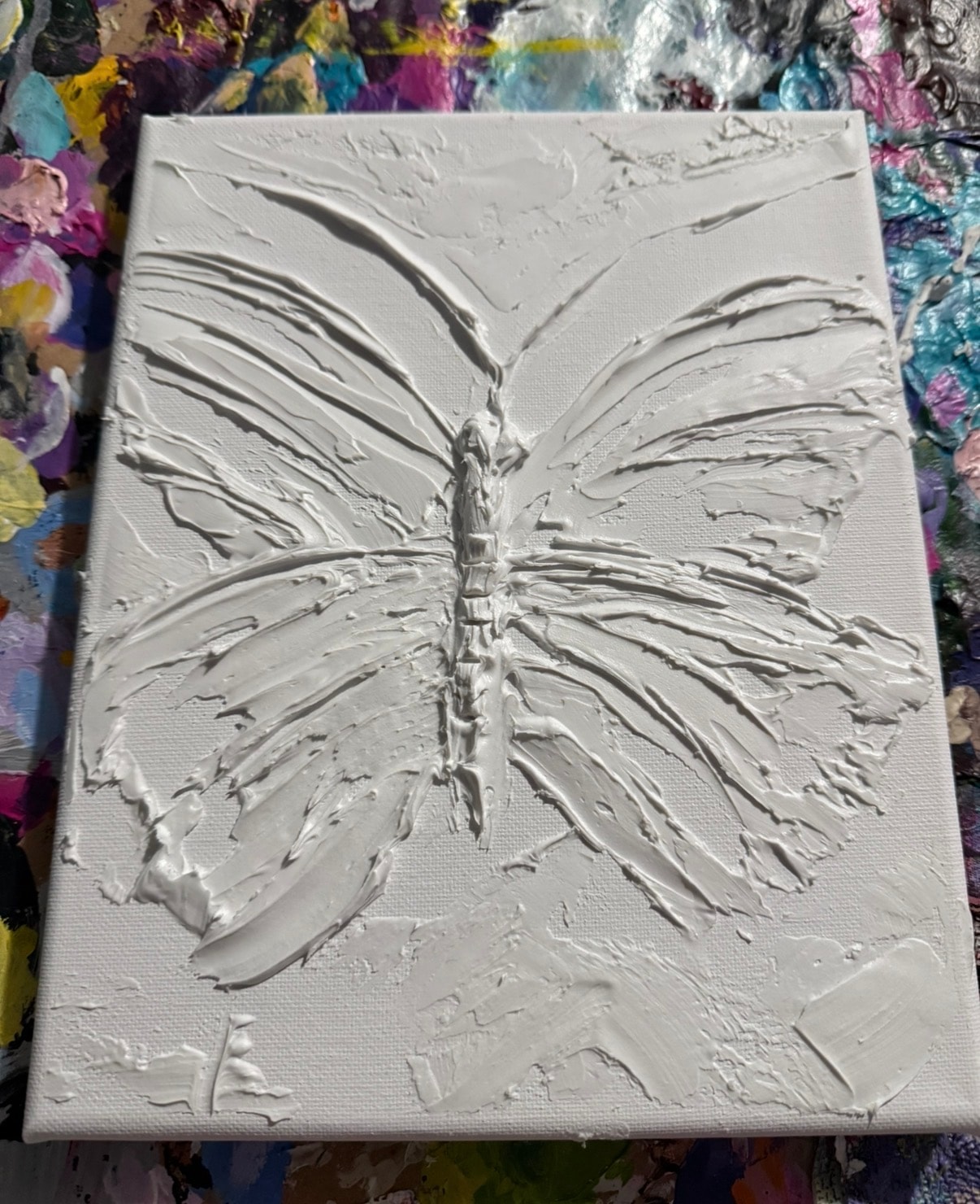 Butterfly caulk art — before painting, white caulk sculpture showing every wing vein and body segment in raised relief